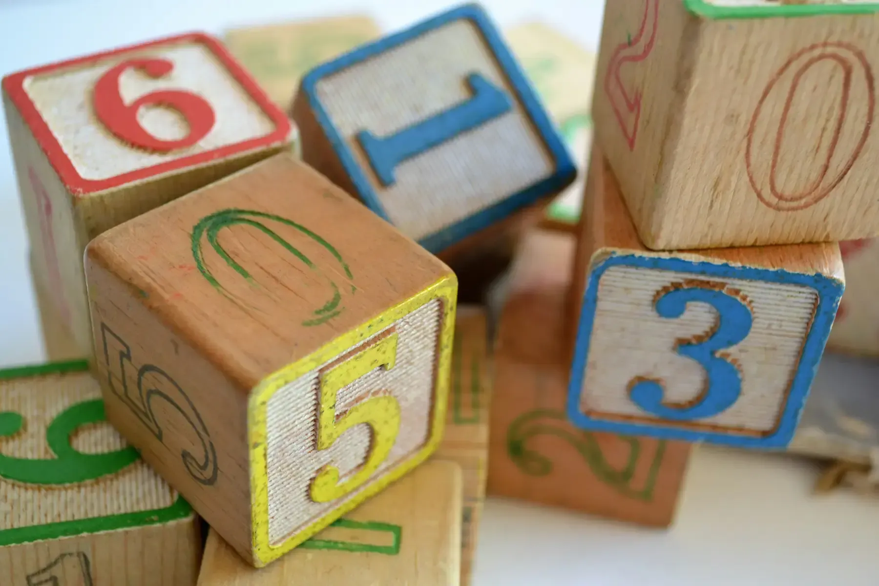 Colorful wooden alphabet and number blocks with red, yellow, and blue borders arranged on a surface